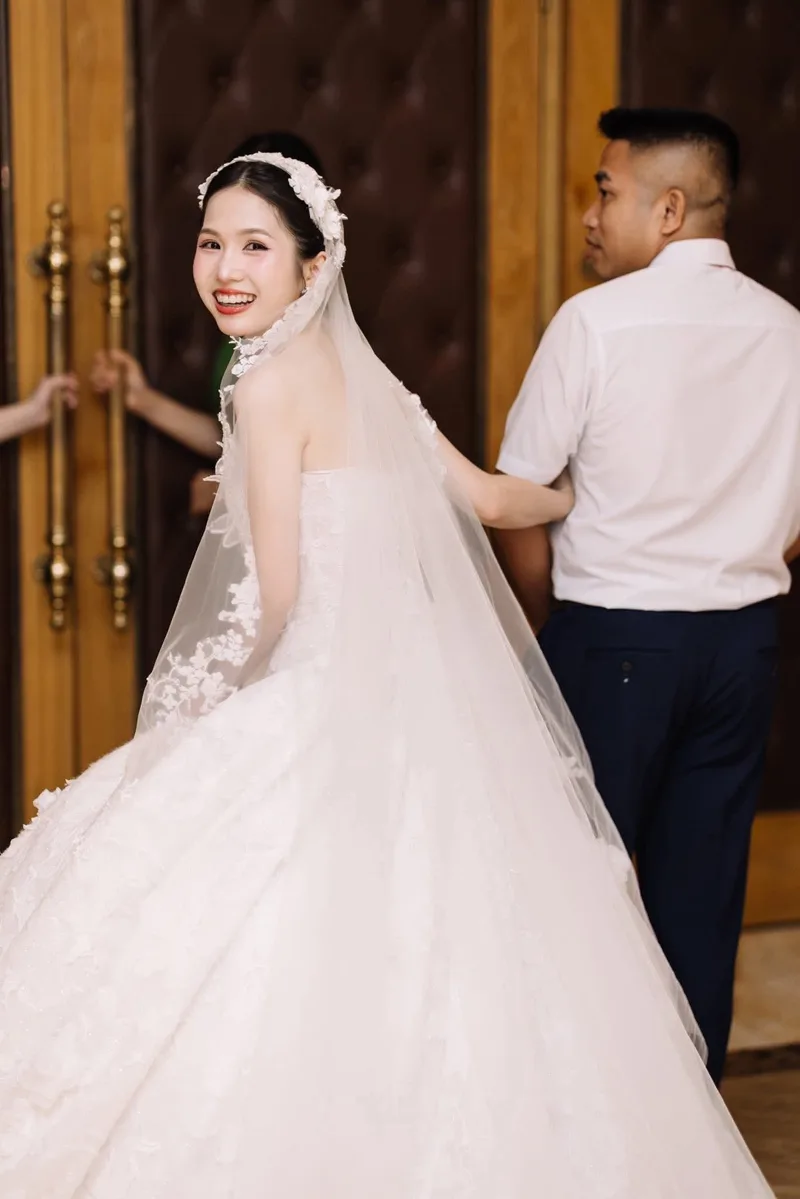 Cô dâu rạng rỡ ngoái lại cười trong ngày cưới, voan ren dài